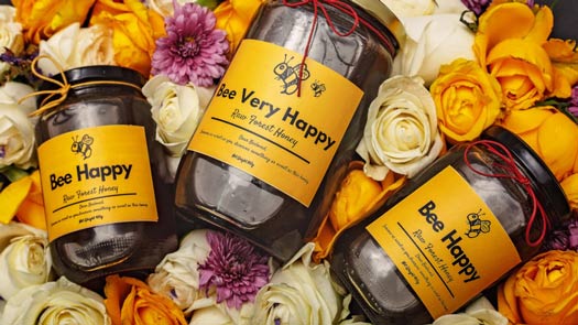 3 jars of honey "bee happy" are on the flowers as a great agriculture business idea